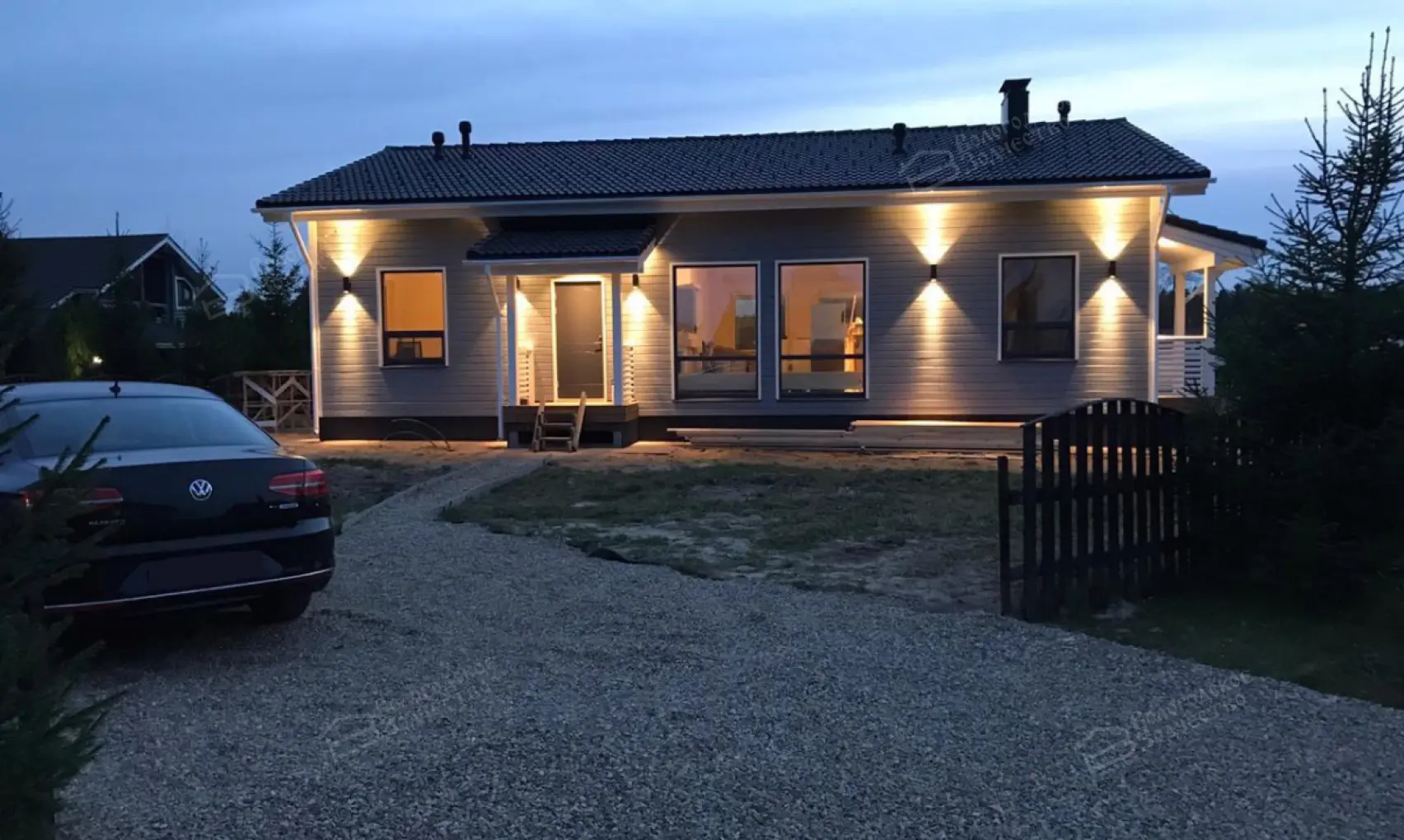Одноэтажный загородный дом с подсветкой фасада в вечернее время
